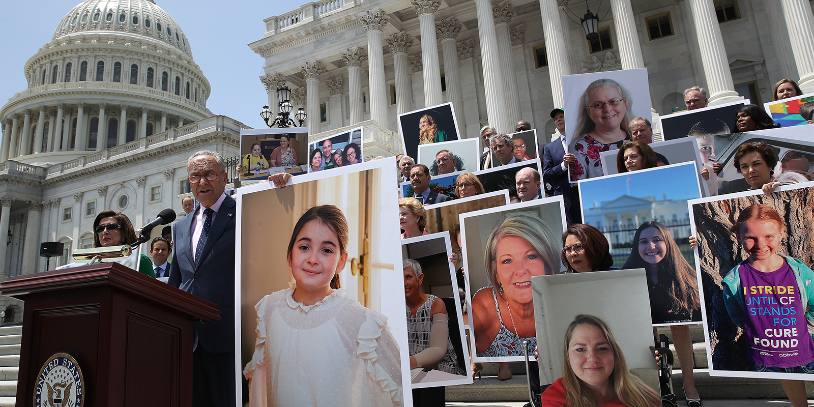 Large pictures of people held up during a speech on government building steps