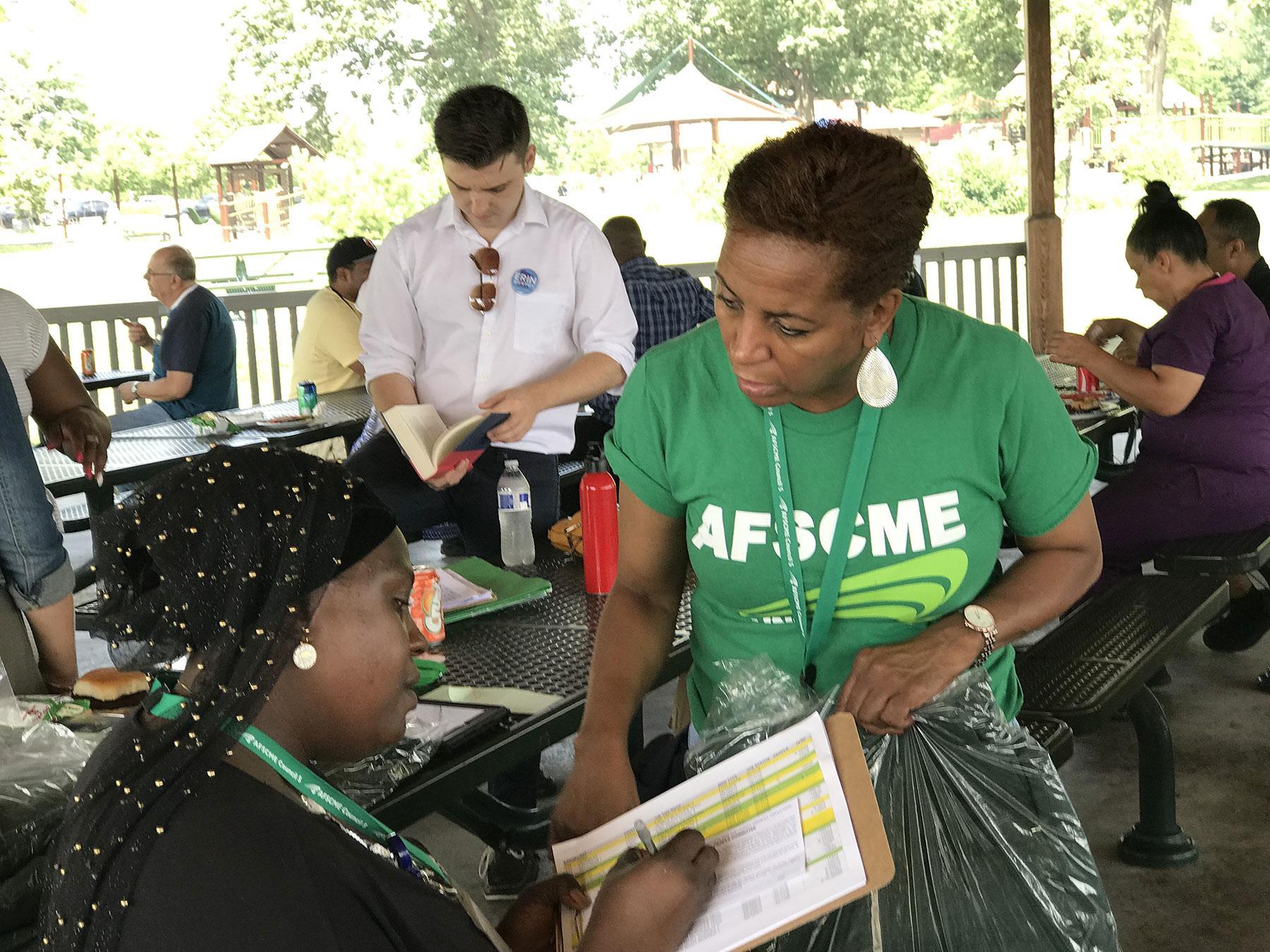 Fatmata Turay signs a PEOPLE card as member organizer Starr Suggs waits to award Turay with a new PEOPLE jacket.